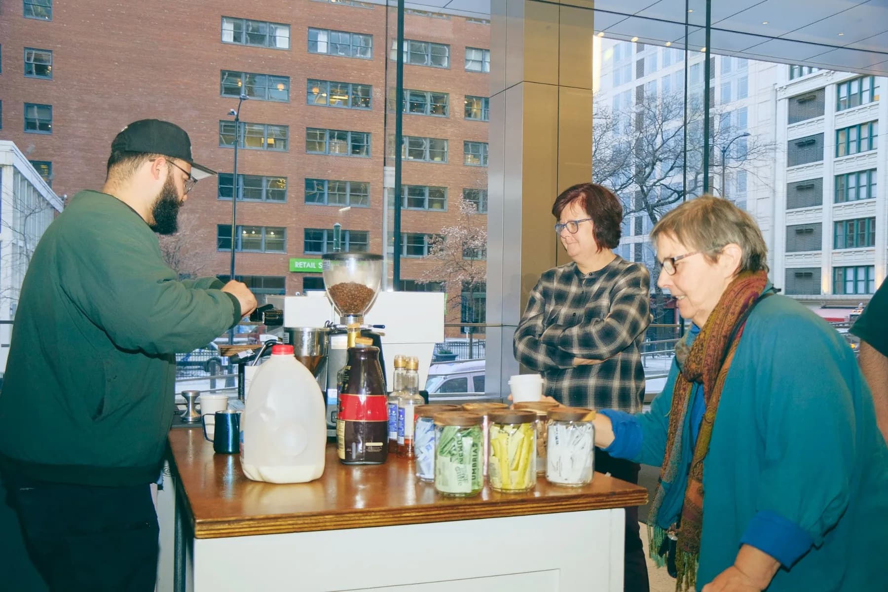 Barista making coffee two women sweeteners lobby