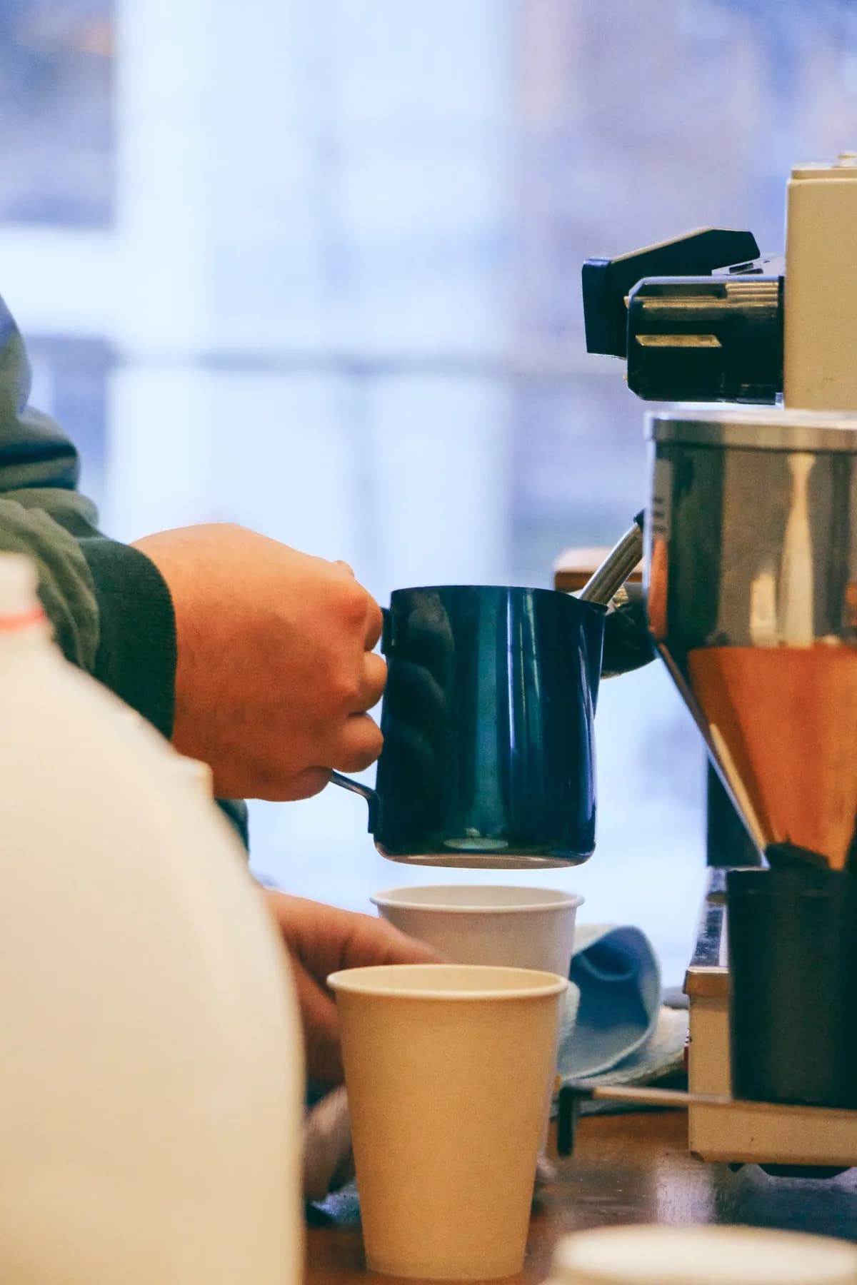 Closeup barista steaming milk into cup